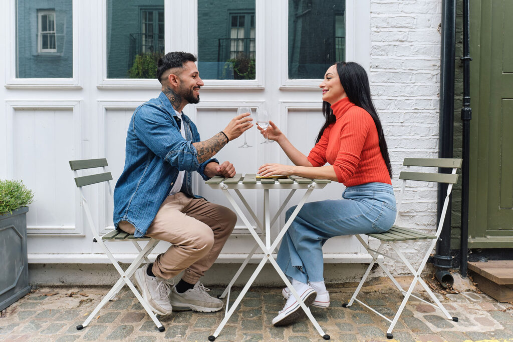 a young couple sitting outside clinking glasses